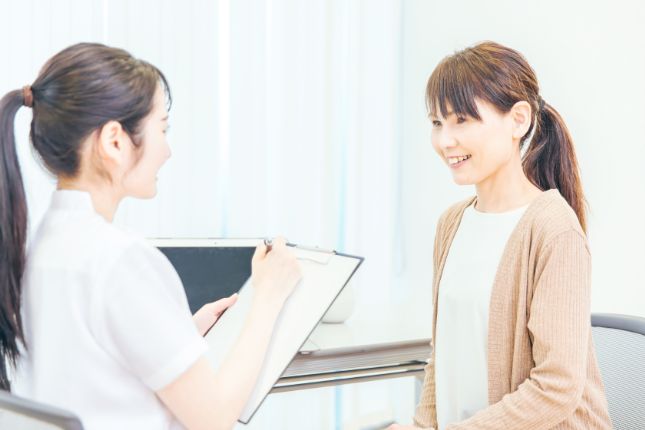 女性患者の問診を行うスタッフ
